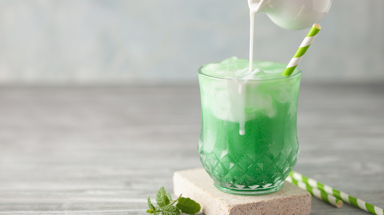 Cream being poured into green soda