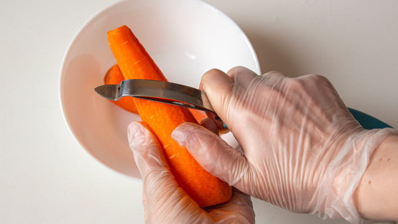 person peeling a carrot