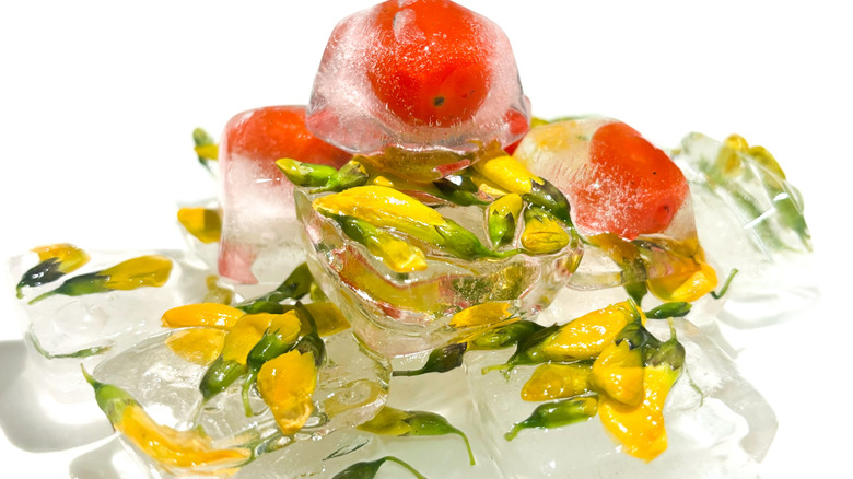 Ice cubes with flowers an fruits frozen into them