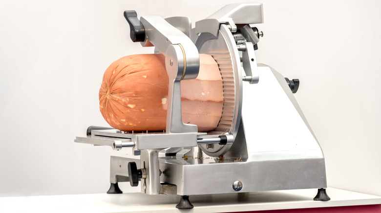 a deli meat slicer with a loaf of bologna on it