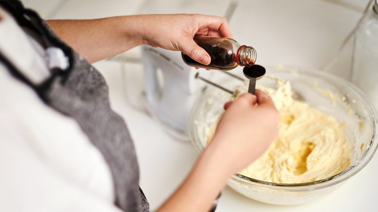 Person adding vanilla extract to bowl