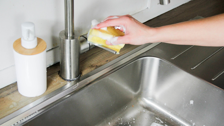 A person cleaning the faucet of a sink