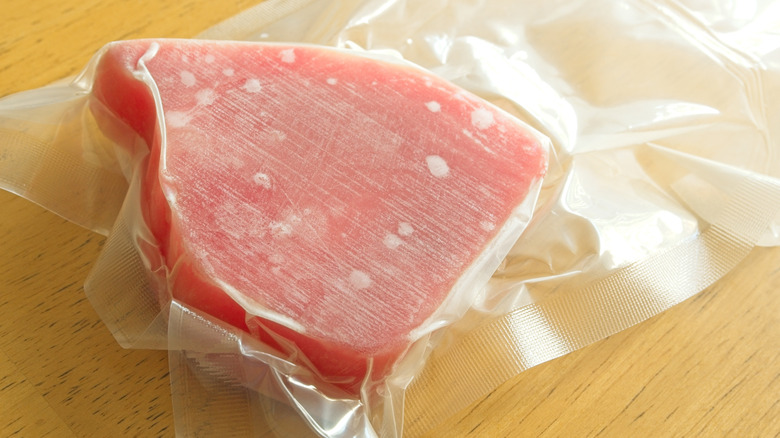 Frozen, vacuum-sealed tuna steak on a wooden countertop