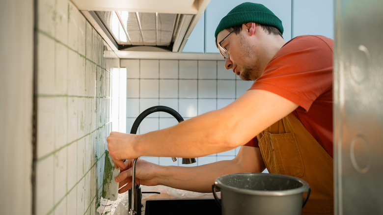 man adds tile backsplash in kitchen