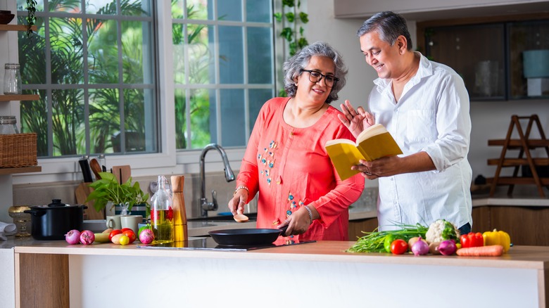 Couple cooking in their home kitchen while consulting the Almanac