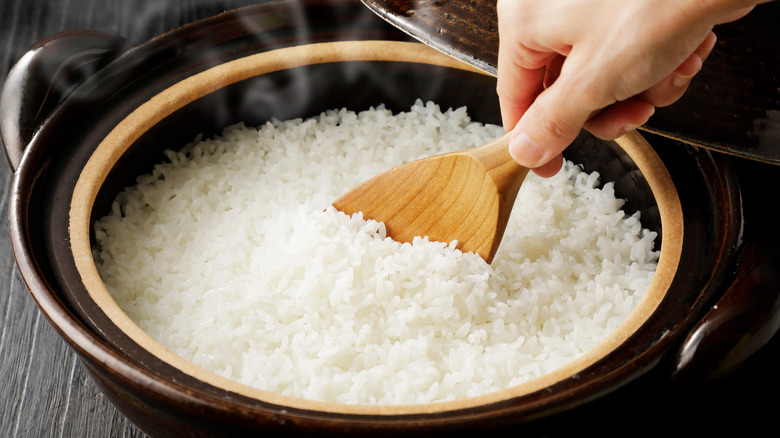 Hand holding a spoon, stirring rice