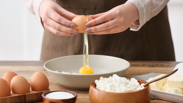 person cracking an egg over a bowl
