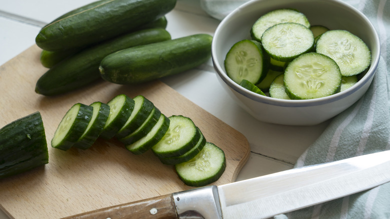 Cucumbers in a bowl next to a knife