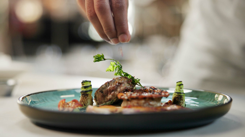 Hand above food sprinkling something into it