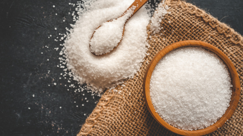 A bowl of salt next to spoon overflowing with salt