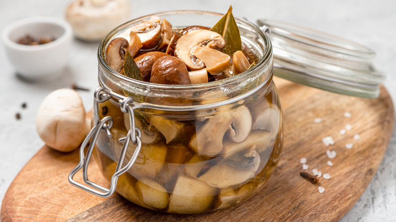 Mushrooms marinating in a jar with bay leaves