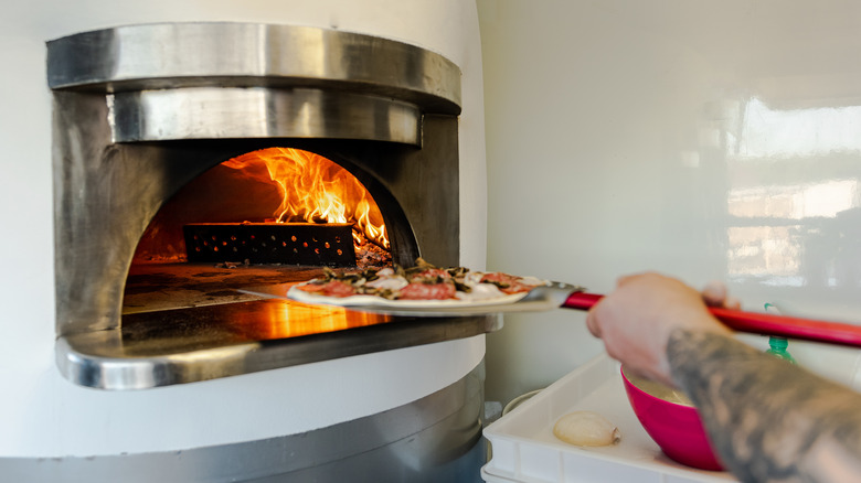 Pizza entering wood-fired oven
