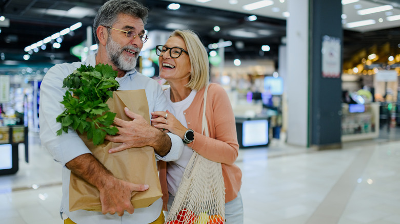 Couple grocery shopping with a full brown paper bag without handles