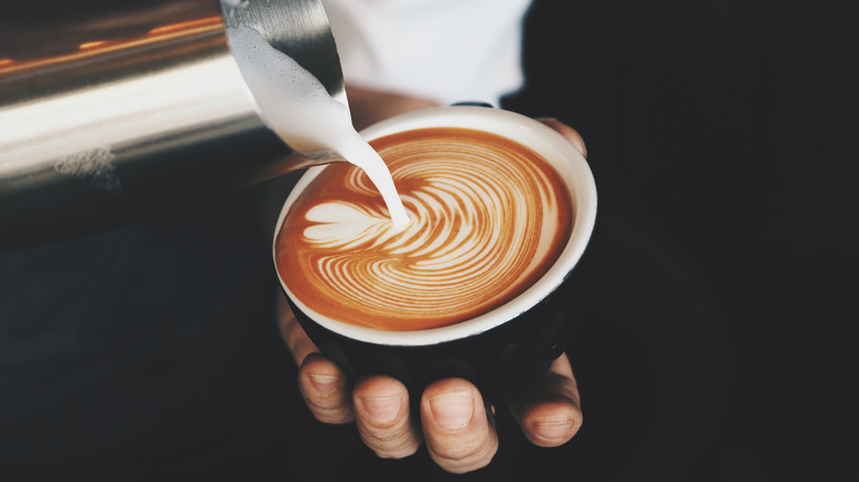 barista pouring coffee into mug