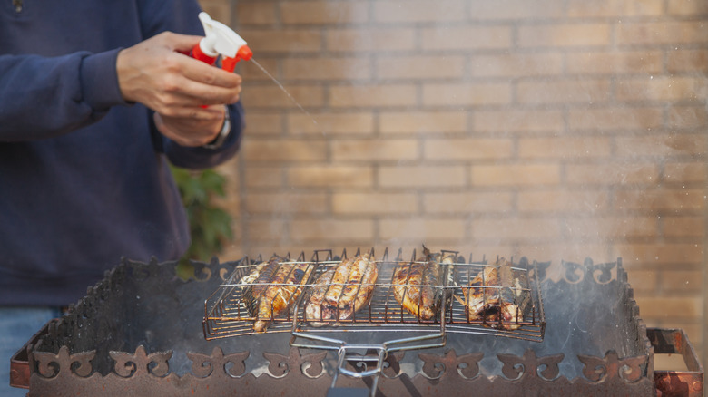 Cooking chicken on grill with spray bottle