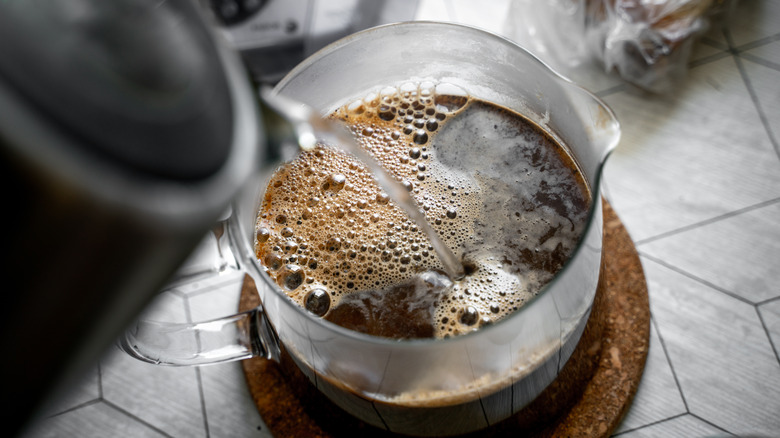 Overhead view of pouring hot water into French press coffee