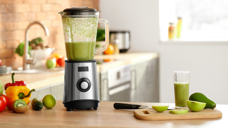 a blender filled with a green smoothie on a table top