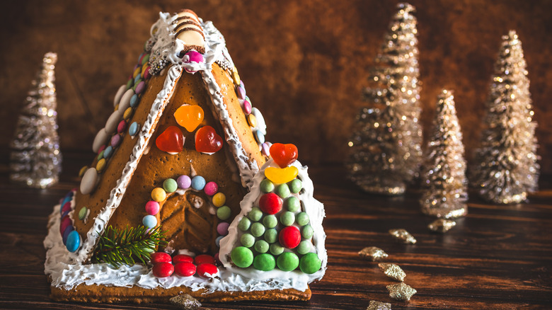 A gingerbread house decorated with multi-colored candies on a wooden table