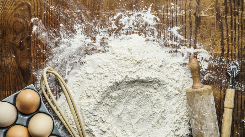 Flour, eggs, and baking tools on table