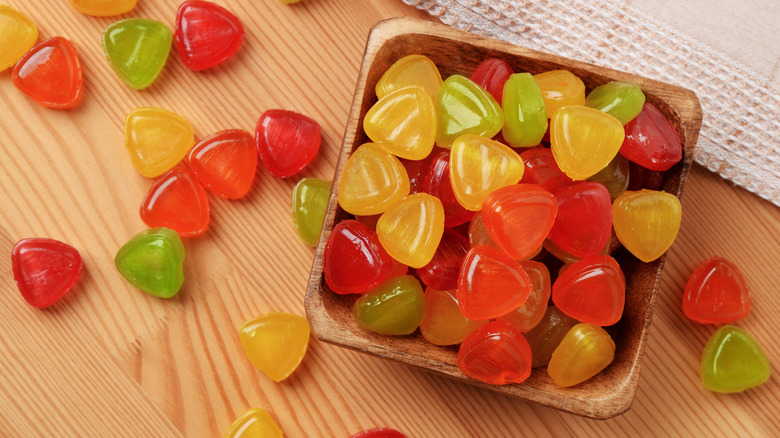 Colorful hard candies in a wooden bowl and strewn around it