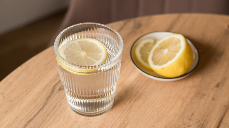 Full water glass next to a bowl of lemon slices
