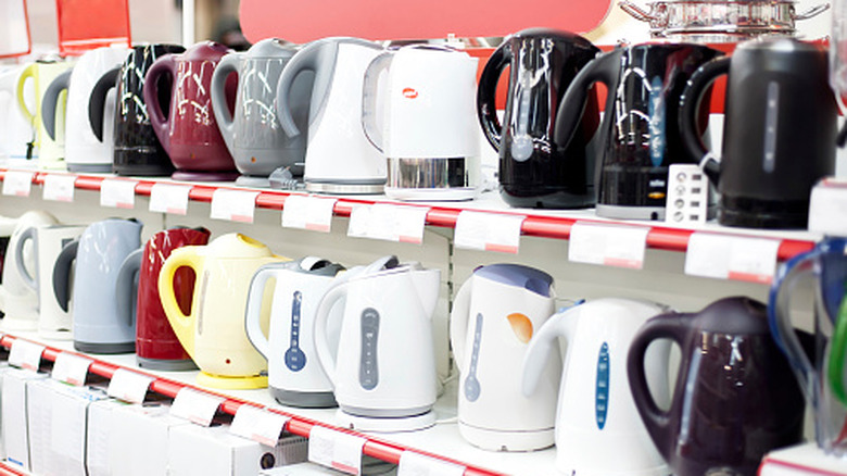 Two shelves of various models and colors of plastic electric kettles