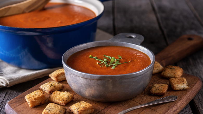 bowl of tomato soup next to pot