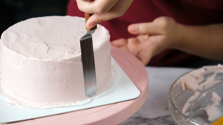 frosting being applied to a cake