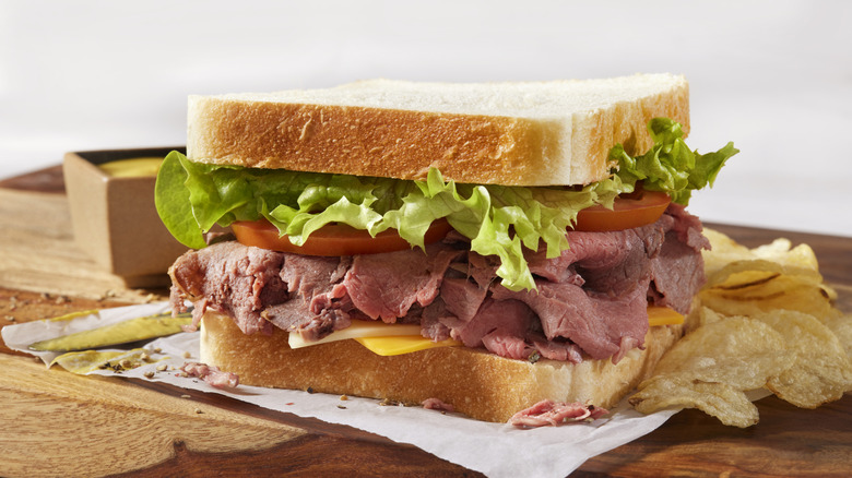 Leftover roast beef in a sandwich next to chips on board