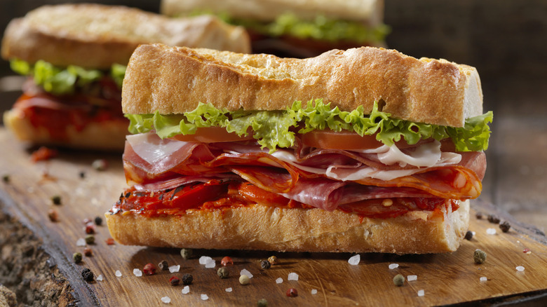 Italian sandwich with deli meats, lettuce, and tomato next to seasonings