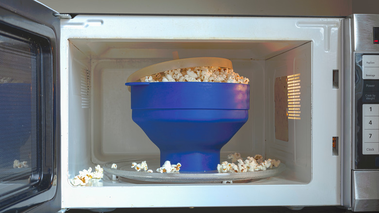 Blue bowl full of popcorn in a microwave