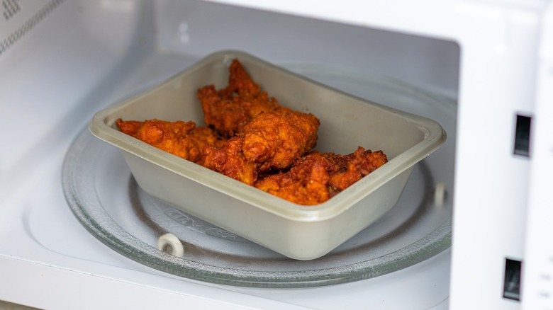 A container of fried chicken in a microwave
