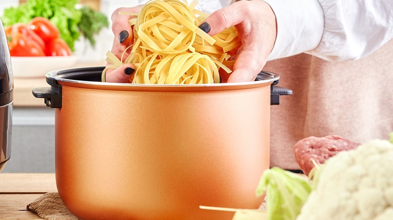 Woman adding pasta to slow cooker