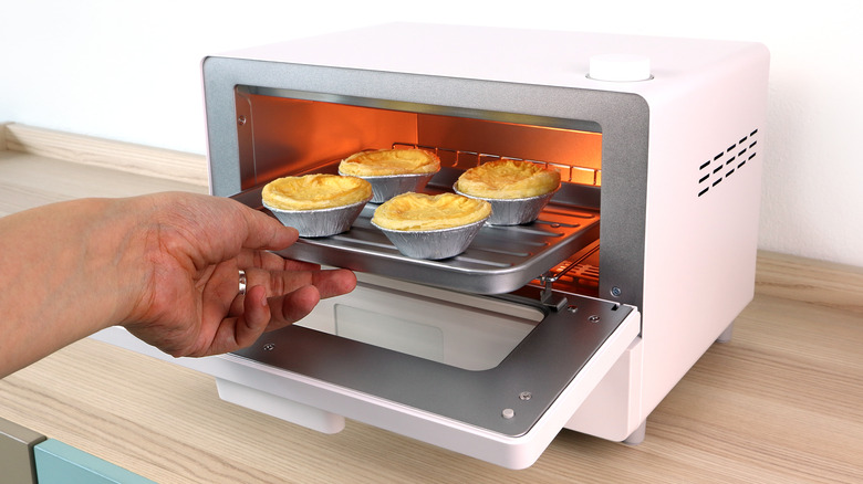 Person putting egg tarts in toaster oven