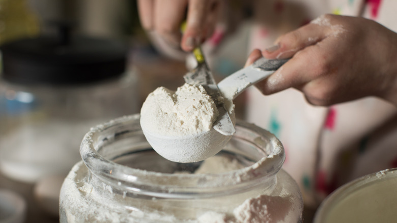 Leveling off a cup of flour over jar