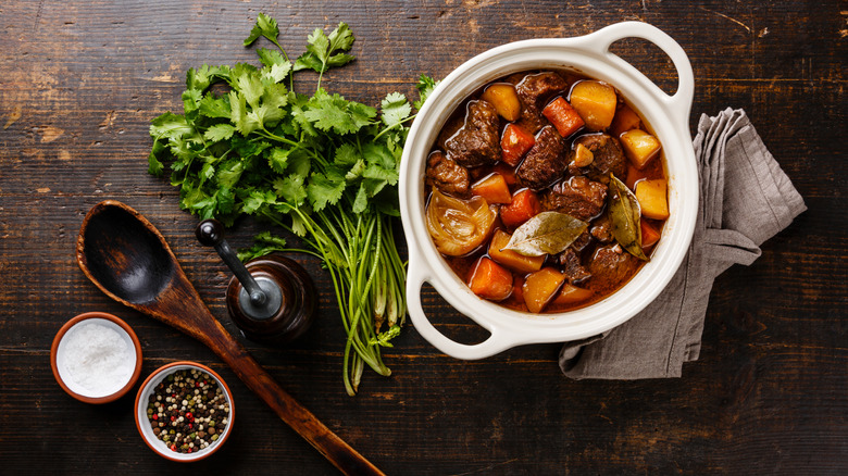 beef bourguignon in a ceramic pot with parsley, salt and pepper