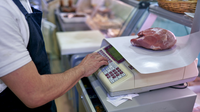 Someone weighing a chunk of meat on a professional scale