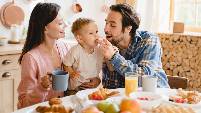 Child being fed food by parents