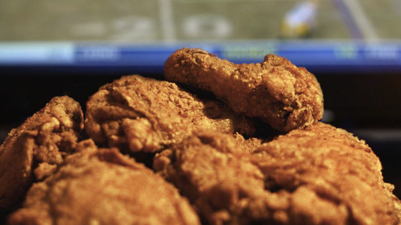Crispy fried chicken in a metallic bucket with sauces in the back