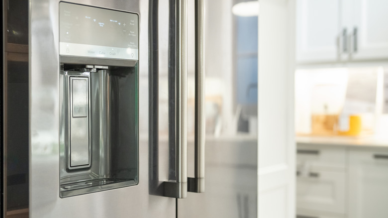 Close-up of an in-door ice dispenser in a stainless steel fridge.