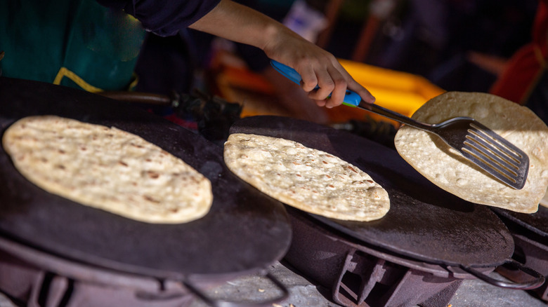 Tortillas being heated and flipped on griddle