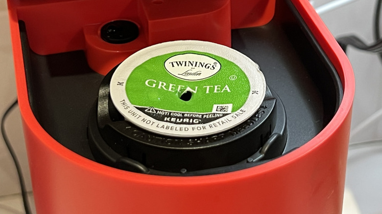 Close up of a red Keurig with a green tea pod inside