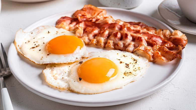 slices of bacon and two fried eggs on a white plate