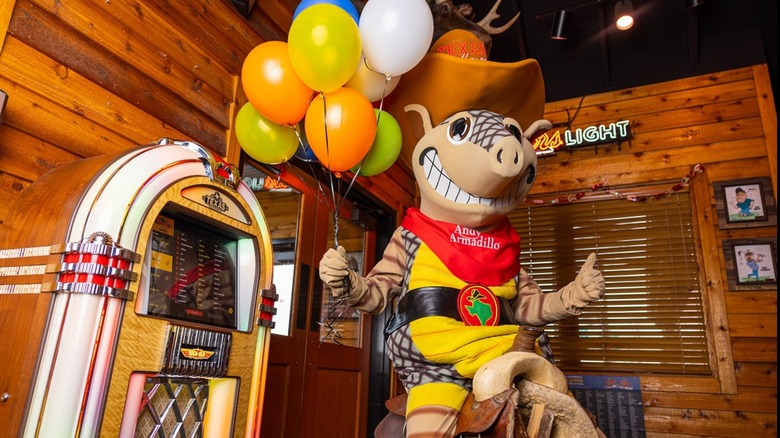 Andy Armadillo in a Texas Roadhouse holding balloons