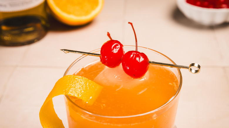 Close up on maraschino cherries and orange peel garnish