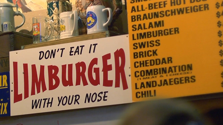 A sign reading "LIMBURGER - DON'T EAT IT WITH YOUR NOSE" next to the menu of Baumgartner's Cheese Store and Tavern in Monroe, Wisconsin