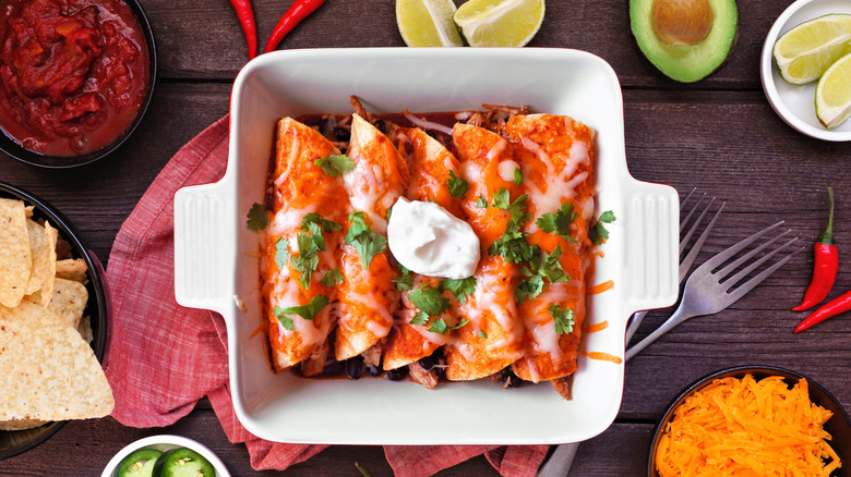 Enchiladas with red sauce and melted cheese in a white baking dish