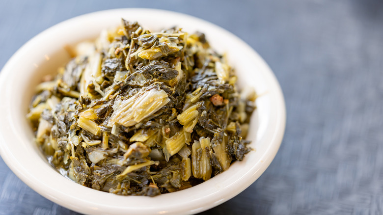 A white bowl of slow-cooked collard greens