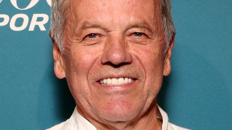 Chef Wolfgang Puck smiles in white chef top