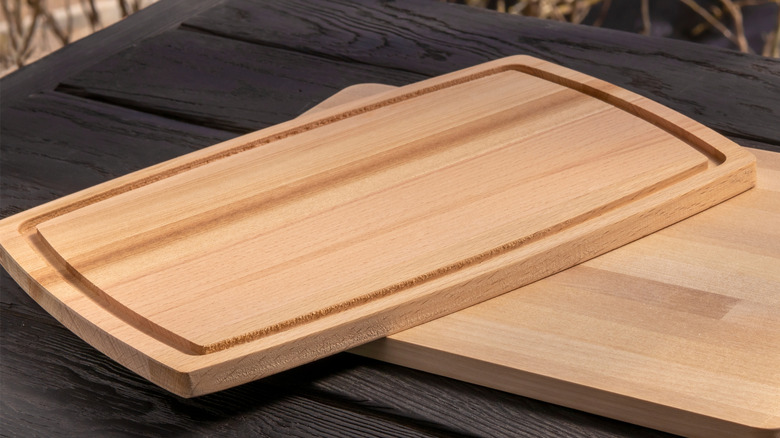 Wooden cutting board with a groove around the outside resting on another cutting board on a wooden table